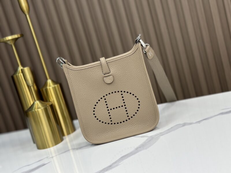 Replica Hermès Gris Tourterelle Clemence Mini Evelyne 16 TPM Bag – High-quality replica Hermès bag in soft Gris Tourterelle Clemence leather with perforated "H" and gold-tone hardware.